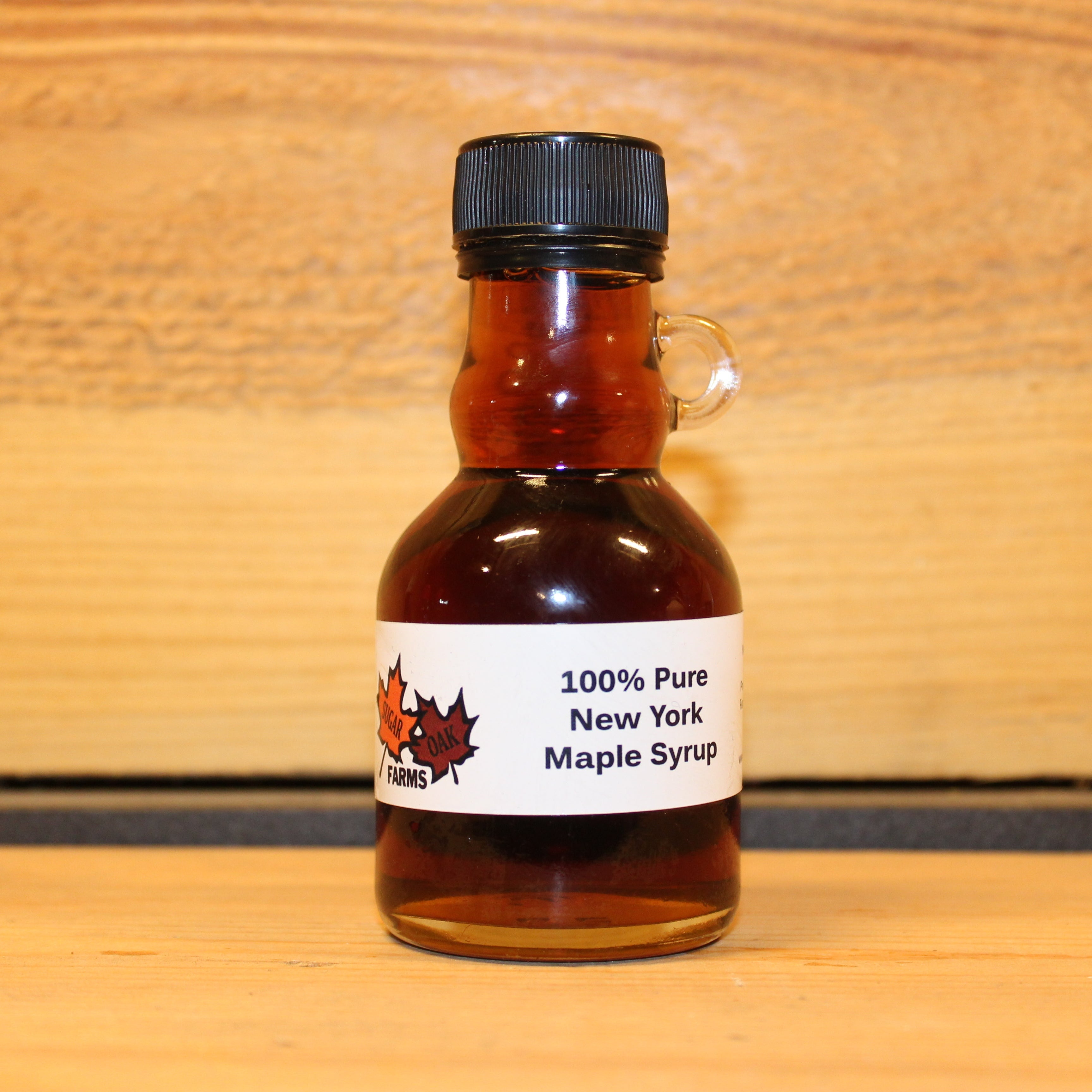 8 fl. oz. glass bottle of dark maple syrup on a wooden surface with a wooden background.